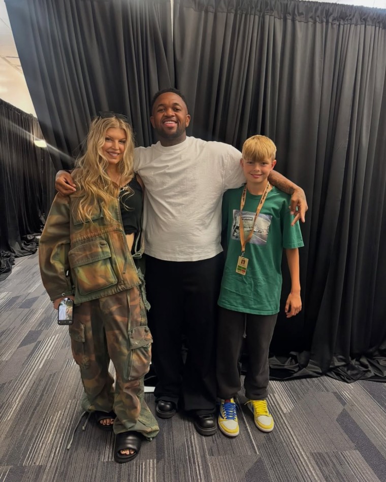 Fergie and her son Axl posing with DJ Mustard backstage.