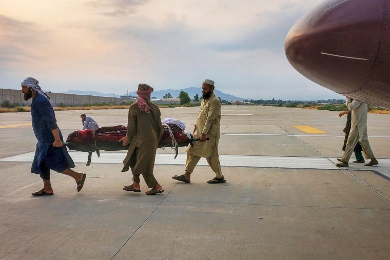 People carry an earthquake victim on a stretcher to an ambulance at an airport in Jalalabad