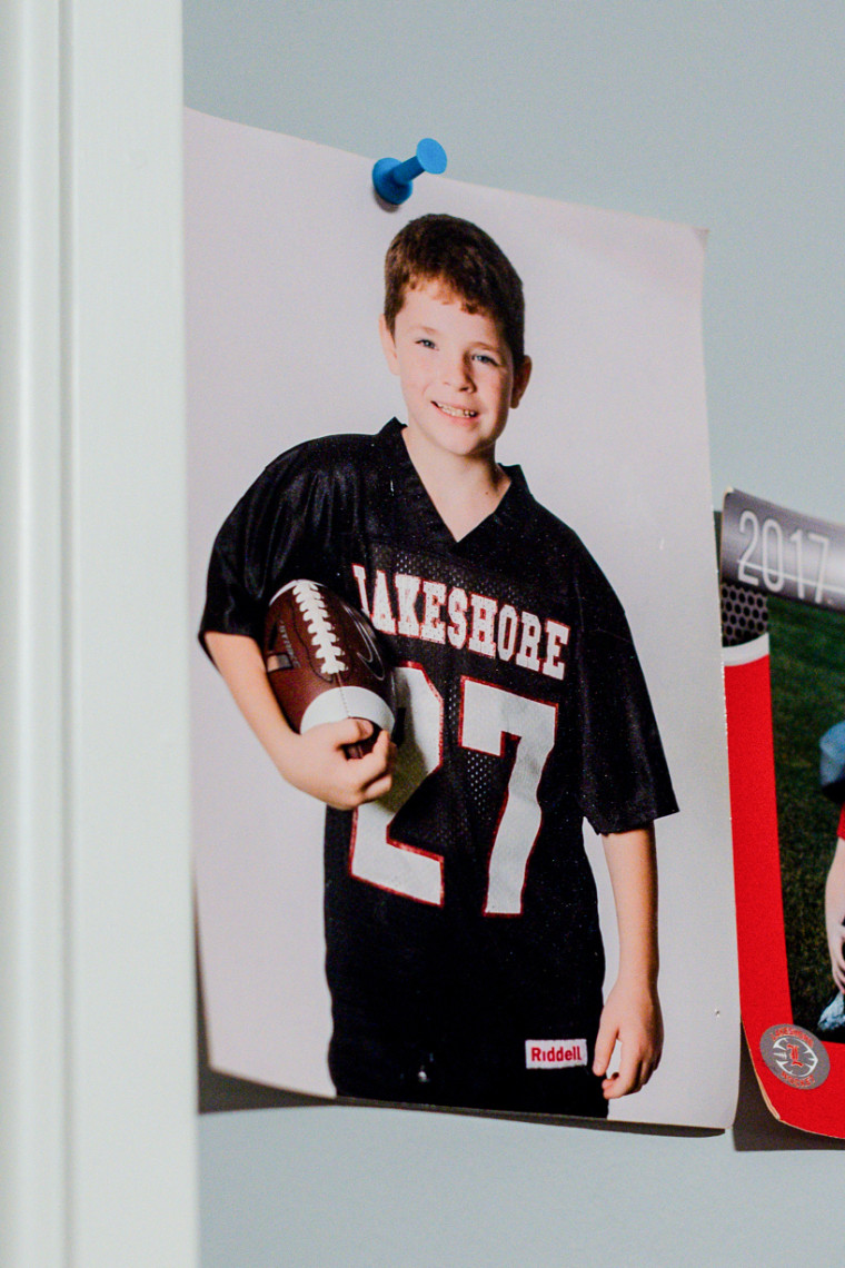A photo of a child holding a football and wearing a black football jersey that reads "Lakeshore #27"