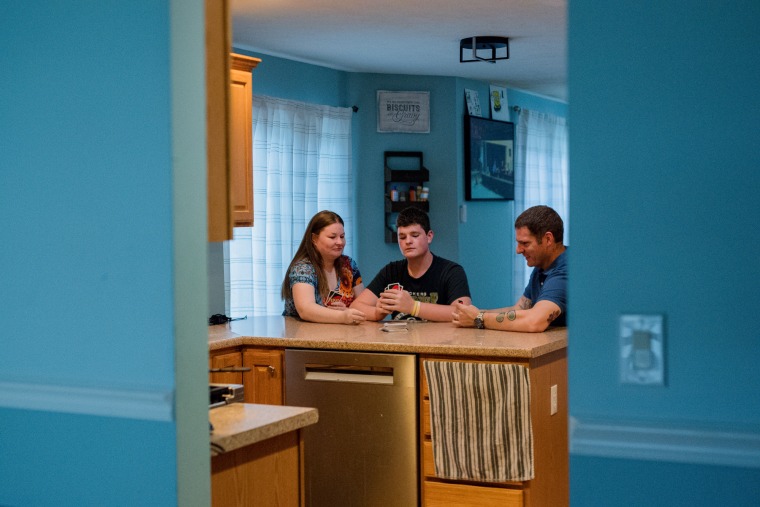 Misty, Jonathan, and Nick Benz-Bushling play Uno at their kitchen counter