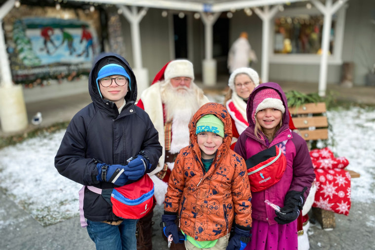 David Haeg, center, and his two siblings pose for a picture outside in winter coats, Mr. and Mrs. Claus stand behind them
