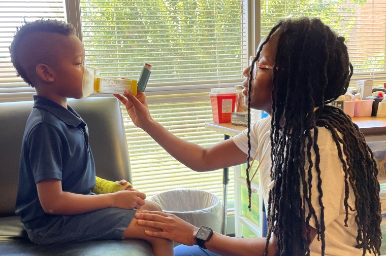 Virginia Wilson helps a young student with a breathing treatment at Premier Charter School in St. Louis.