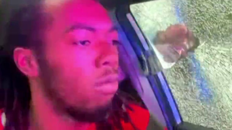 William McNeil Jr seated in a car as a fist goes through his side window