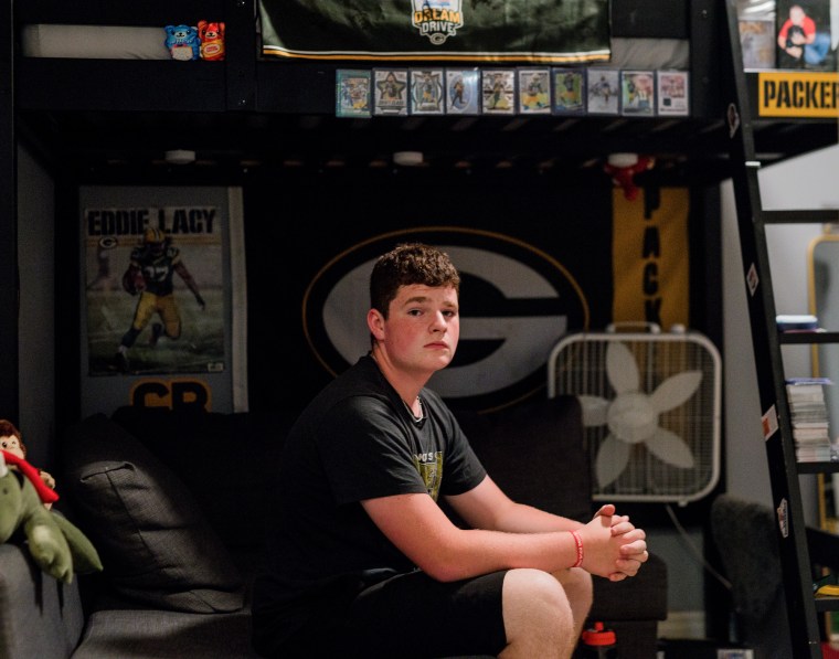 Jonathan sits on his bed and poses for a photos