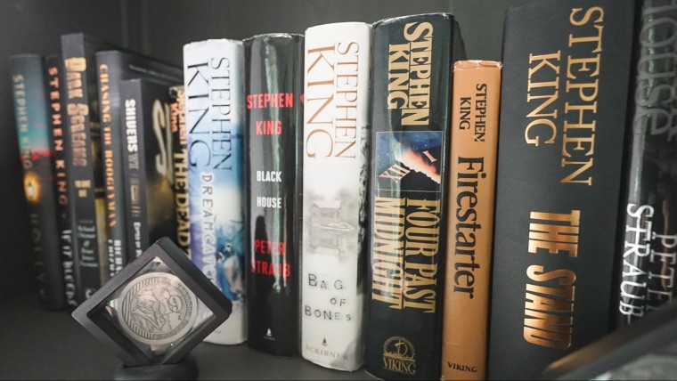 A row of Stephen King novels in a black bookshelf