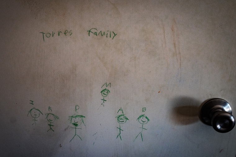 Green stick figures are drawn on a door with drawn text above the figures that reads "Torres family"