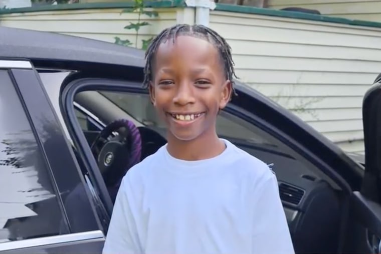 Sakir Everett smiles while standing near a car with the passenger car door open
