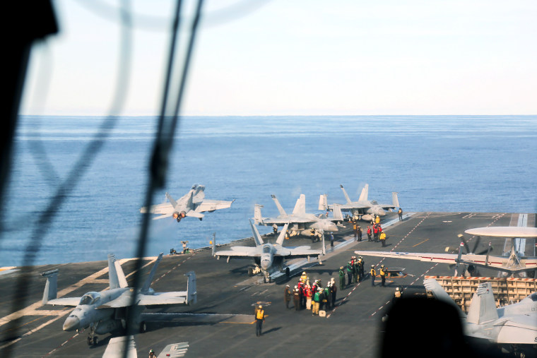 A F-18 fighter jet takes off from the Ford as others planes prepare for flights.