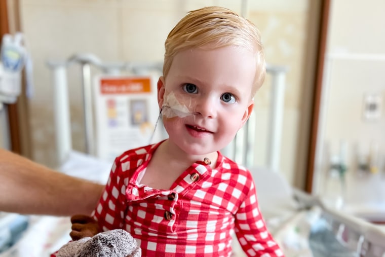 Beckett Wear sits on a hospital bed with a tube entering his nostril taped to his face