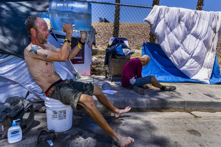 Homeless man Milton John Scott III pours a jug of water on his head to cool off