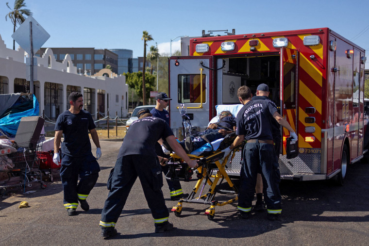 Firefighter EMT personnel assist a man who collapsed during a 27-days long heat wave with temperatures over 110 degrees Fahrenheit near downtown Phoenix, Arizona, on July 26, 2023.