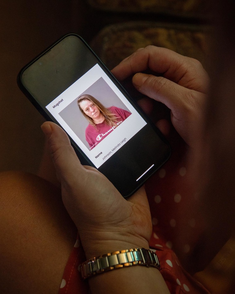 Melinda Johnson holds her phone showing a photo of her incarceration mugshot.