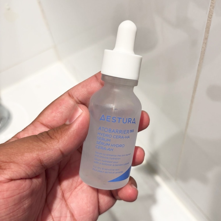 Person holding clear bottle of the Aestura Atobarrier serum.