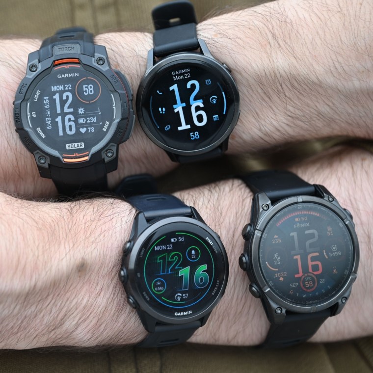 A close up of four different Garmin watches on the wrists of the writer.