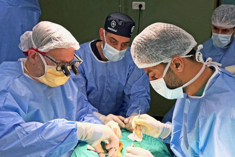 Dr. Feroze Sidhwa, center, assists with a surgery in Gaza.