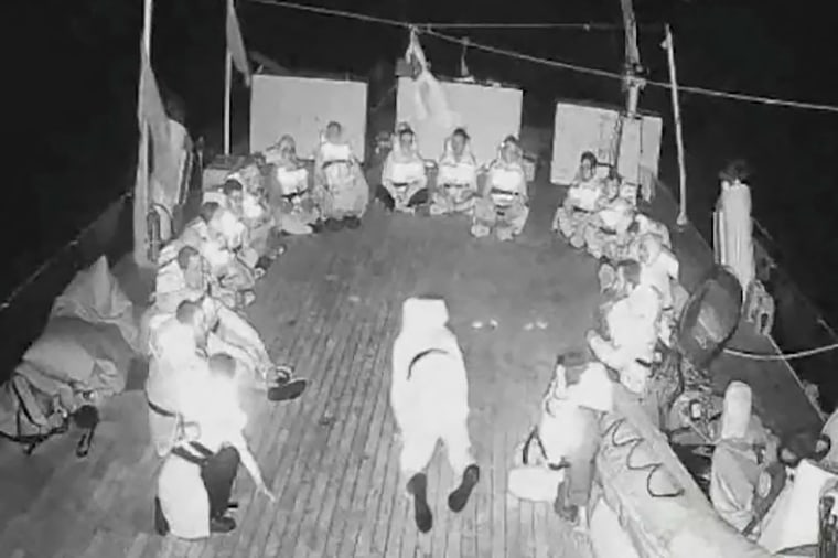 Orang -orang duduk dalam lingkaran di atas Alma, sebuah kapal yang merupakan bagian dari armada dunia Sumud