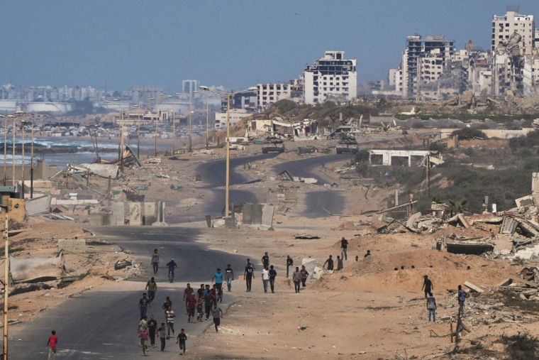 Israeli tanks block the beach road to Gaza City as displaced Palestinians walk on the coastal road near Wadi Gaza on Thursday, Oct. 9, 2025. 