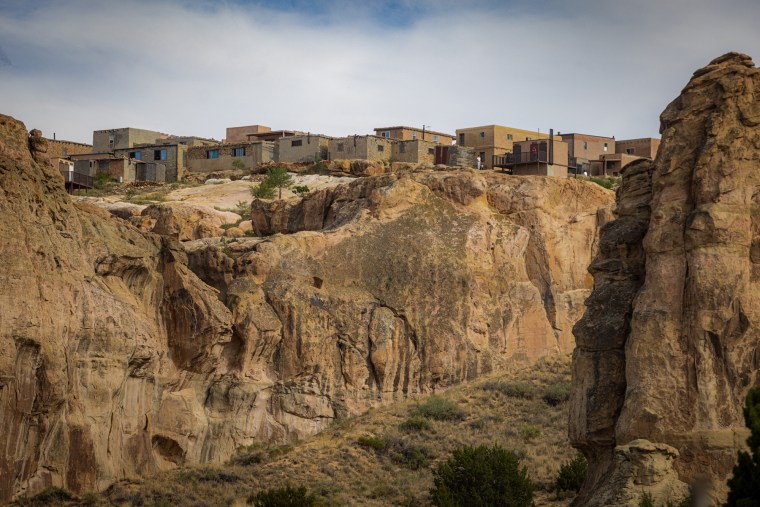 A view of houses on top of a tall mesa rock structure