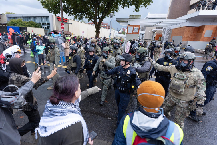 ICE officers push protesters out of the street in front of the ICE facility in Portland, Ore., on Sunday, Oct. 12, 2025.