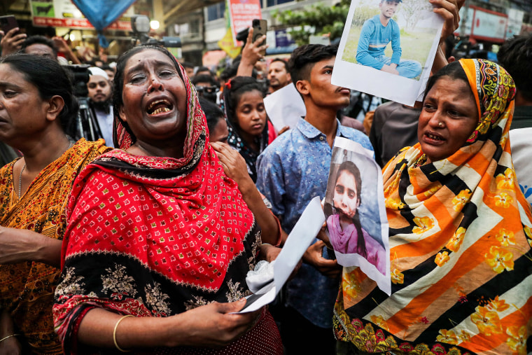 Women crying as they show photographs of fire accident victims