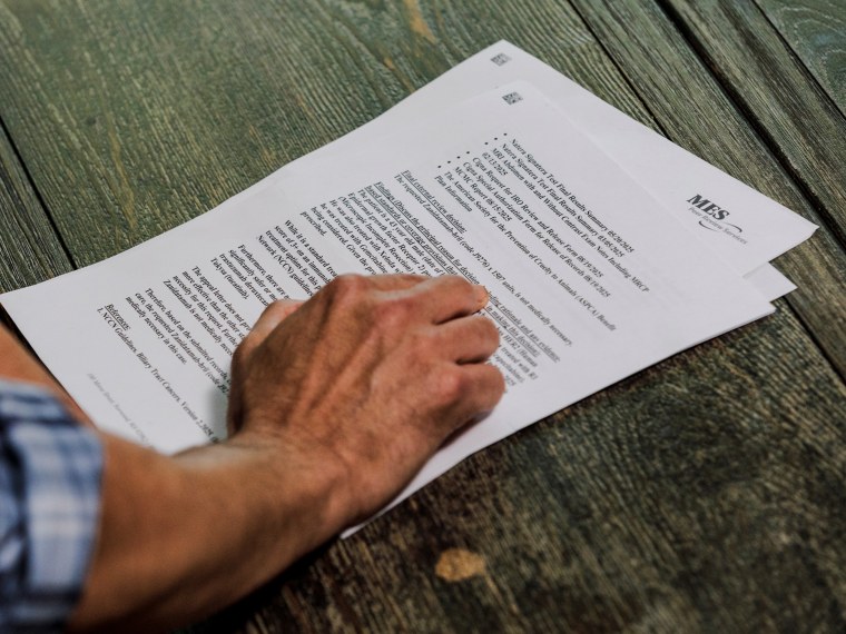 A hands points to words on an insurance denial letter laid on a wooden surface