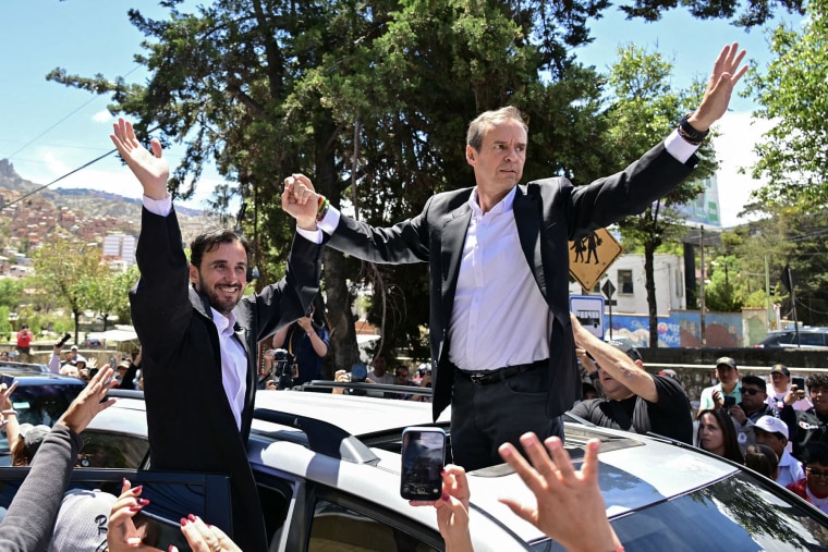 Bolivian presidential candidate Jorge "Tuto" Quiroga and his running mate, Juan Pablo Velasco, greet supporters after voting in La Paz