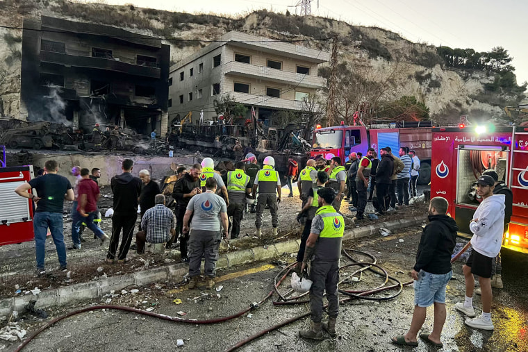 Rescuers and first-responders stand outside a damaged building following an overnight Israeli strike in Msayleh, southern Lebanon, on Oct. 11, 2025. 
