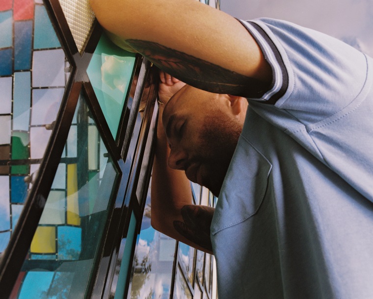 Giuseppe Corletto leans against a stained glass wall