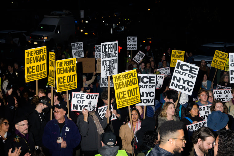 People hold anti-ICE signs outside