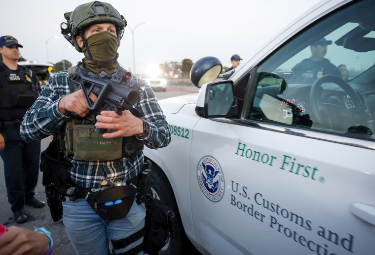 Boarder Patrol agent holds a gun.