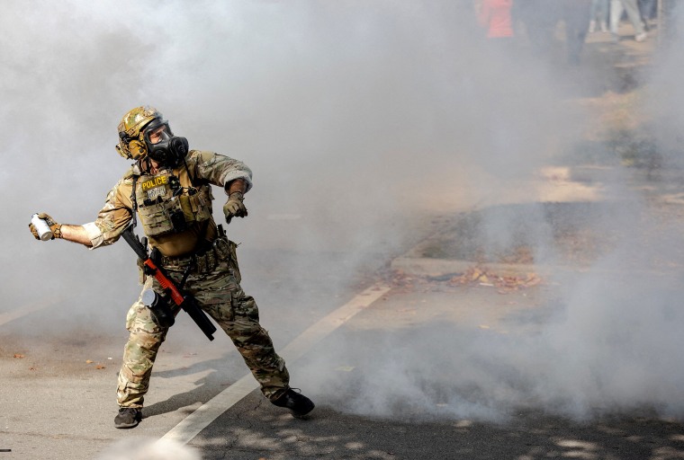 A federal agent throws a tear gas canister during clashes with community members on Chicago’s South Side on Oct. 14. 