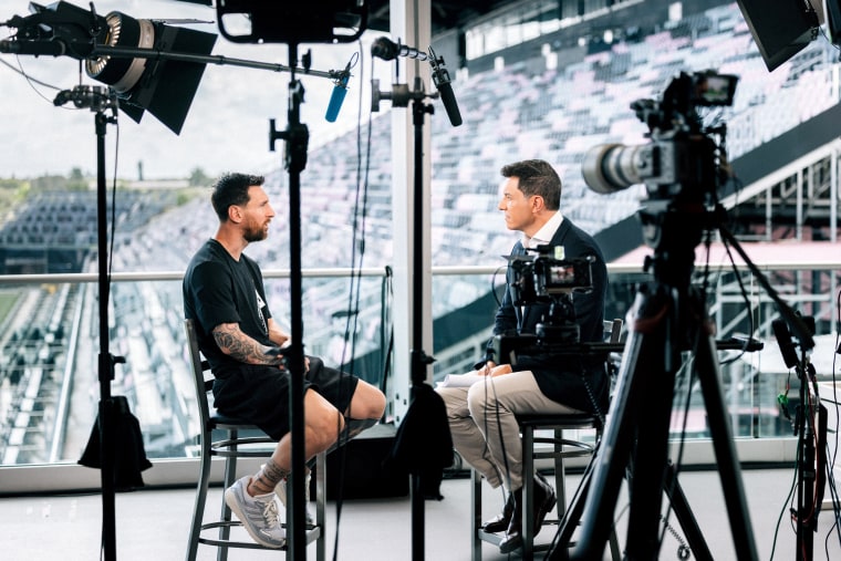 Lionel Messi and Tom Llamas surrounded by cameras and lights
