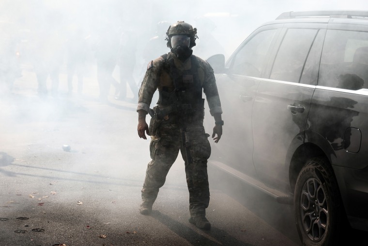 A Border Patrol agent walks through a cloud of tear gas after agents faced off against community members.