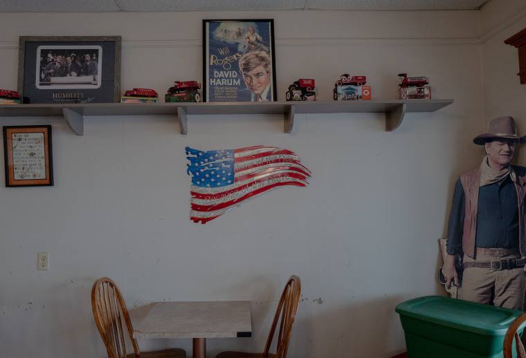 A tin flag on the wall of at a Coney Island hot dog restaurant, reads "Home of the Free, Because of the Brave."