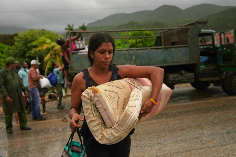 Una mujer que lleva un colchón bajo la lluvia evacúa antes de la llegada del huracán Melissa en Cañizo, una comunidad de Santiago de Cuba, el martes 28 de octubre de 2025.