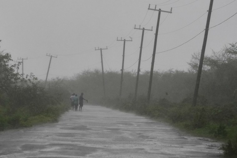 Varias personas caminan junto a una carretera durante el paso del huracán Melissa en Rocky Point, Jamaica, el 28 de octubre de 2025.