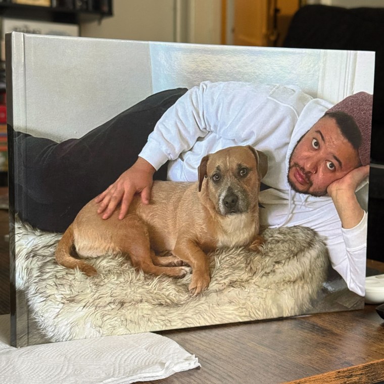 Man holding photo book with cover photo of him and his dog