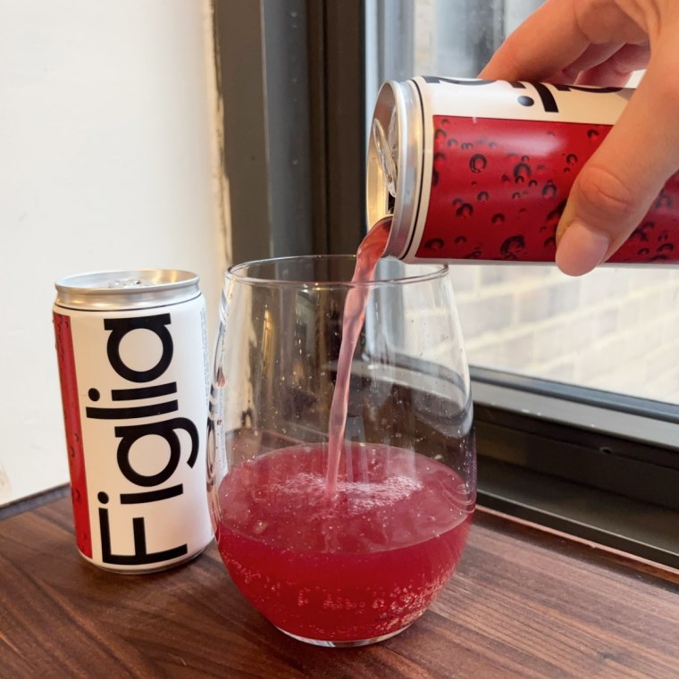 A hand pouring Figlia’s Fiore Frizzante into a glass cup with a can of the drink behind it.