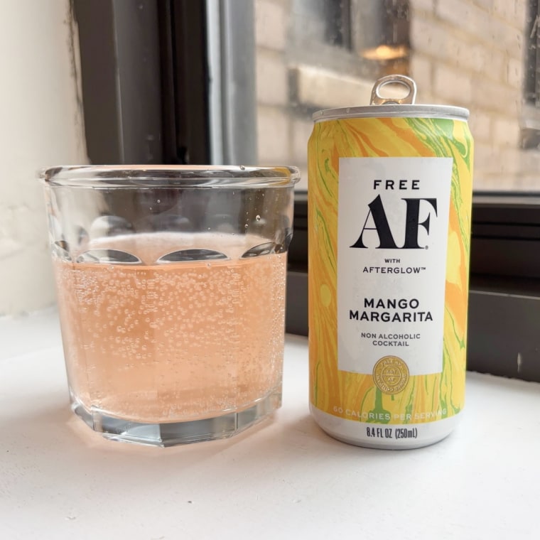 A can of Free AF’s mango margarita standing up next to a glass cup filled with the drink.