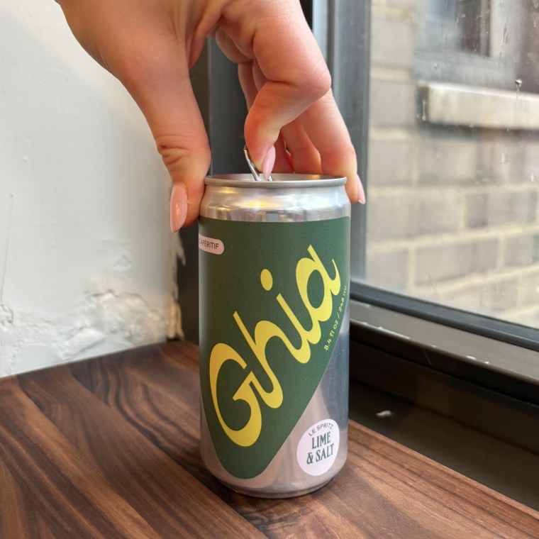A hand opening a can of Ghia’s Le Spritz Lime & Salt.