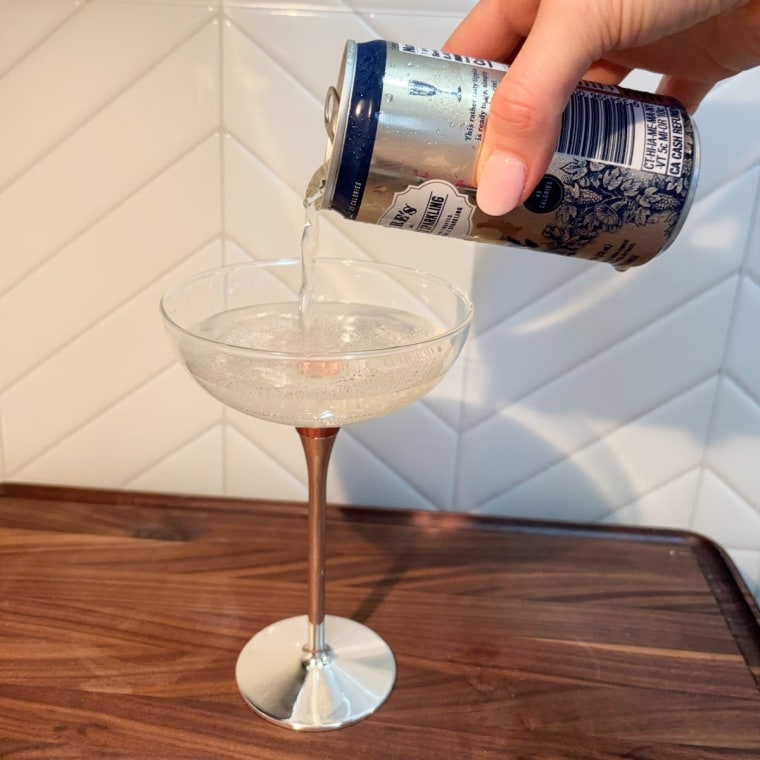 A hand pouring a can of Lyre’s Classico Sparkling into a glass.