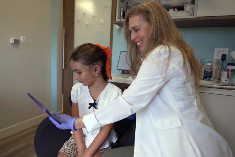 Lewin shows Olivia her new ear for the first time.