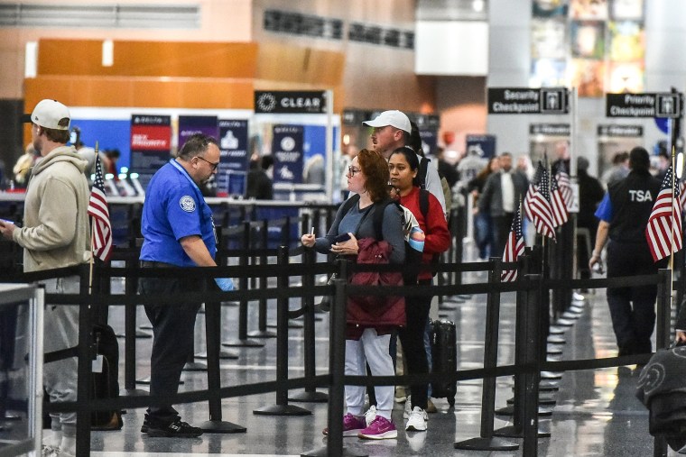 Image: Travelers make their way through a security line