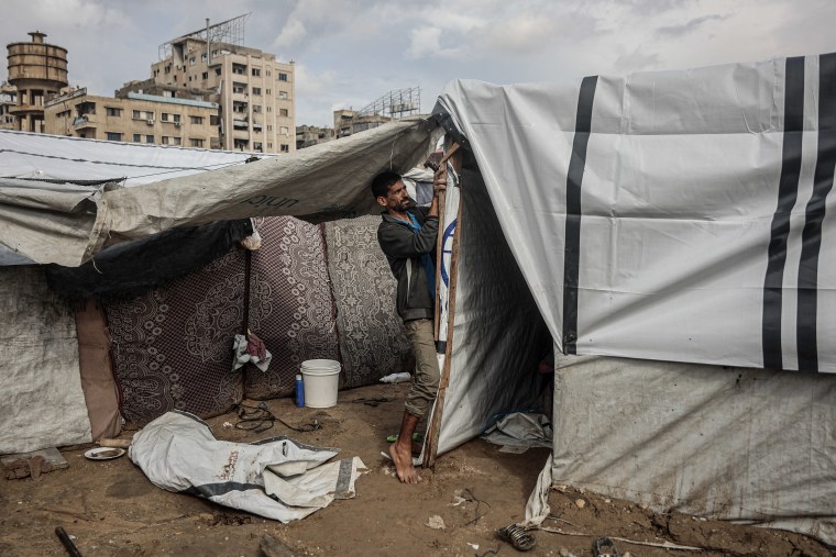 A Palestinian man fixes his makeshift shelter as the first winter rains fall on a displacement camp in Gaza City on Friday.