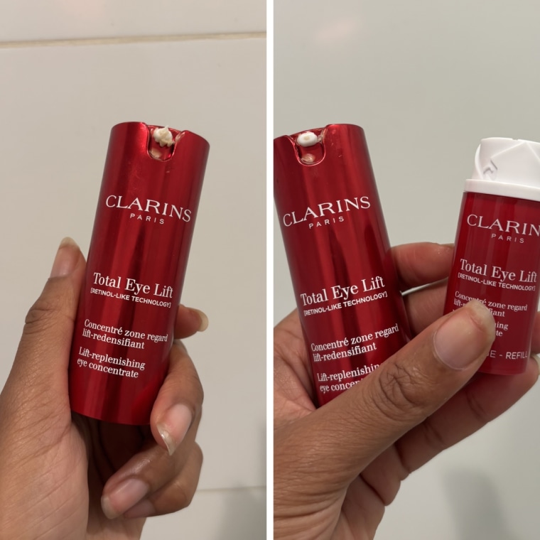The Clarins Total Eye Lift in a hand in front of a white tiled bathroom wall.