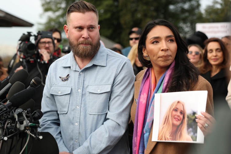 Sky Roberts, brother of Virginia Giuffre, who was abused by Jeffrey Epstein, stands with his wife Amanda Roberts, who holds a photo of Giuffre, during a news conference on the Epstein Files Transparency Act outside the U.S. Capitol on November 18, 2025.