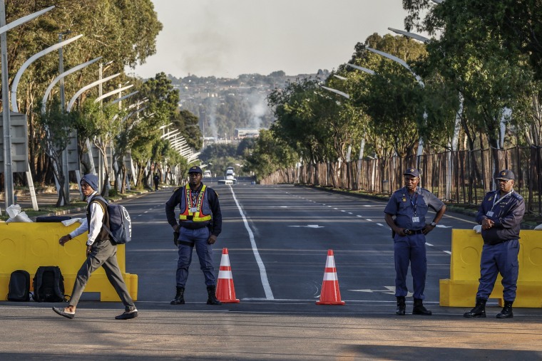 A pupil crosses a road as South African Police Service officers monitor the area near the Nasrec Expo Centre in Johannesburg on Nov. 22.