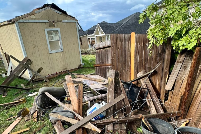 Pieces of a broken fence can be seen near a shed outside in yard