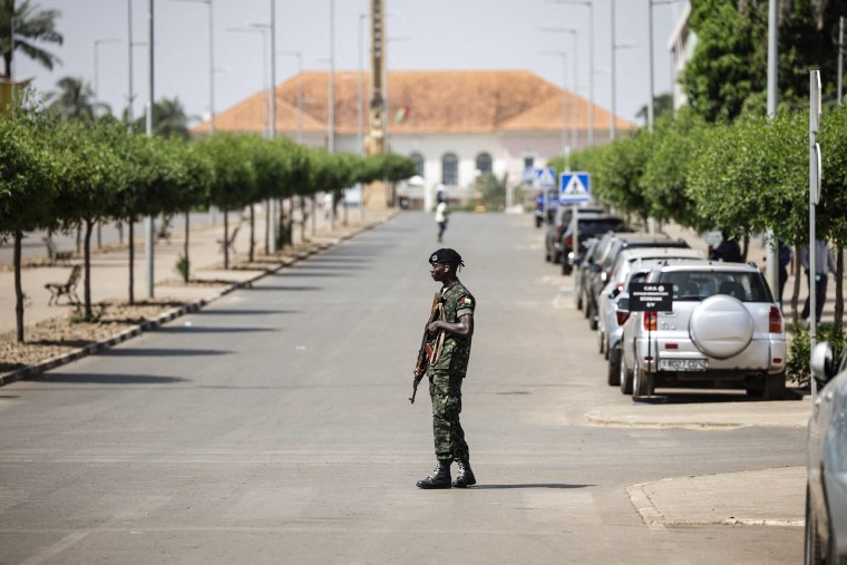 Image: A soldier holds his weapon while patrolling a street near the scene of gunfire near the Presidential Palace in Bissau