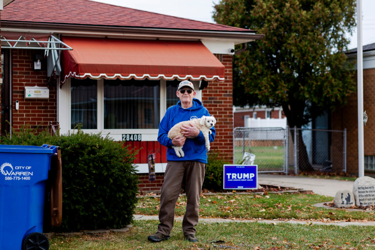 Jim Klotz stands in front of his home with his dog in his arms